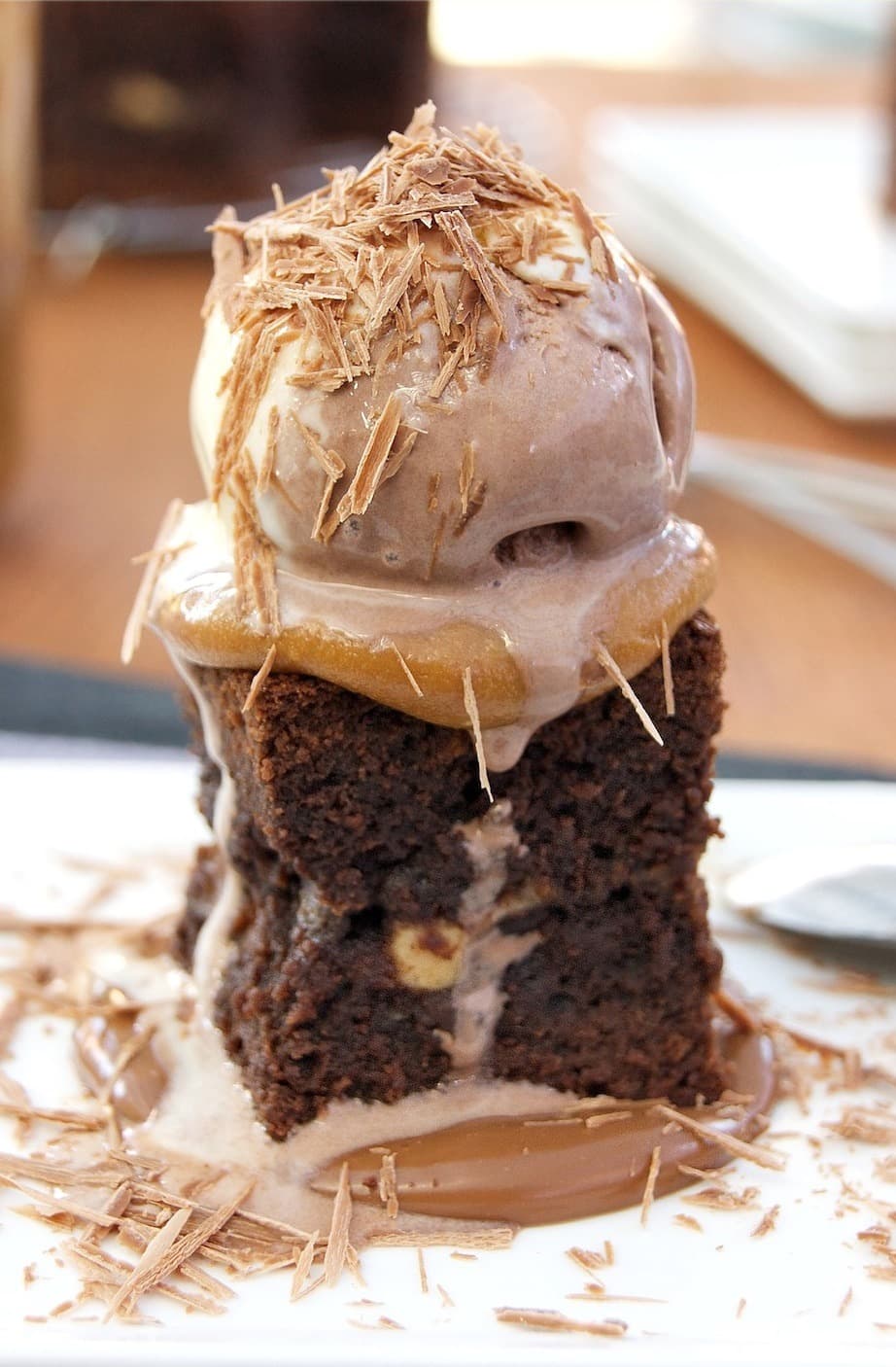 A peanut butter brownie topped with dulce de leche, ice cream, and chocolate shavings